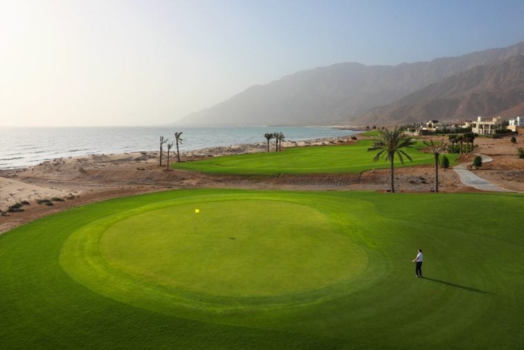 Jebel Sifah 7th green against a stunning backdrop of mountain terrain and seafront